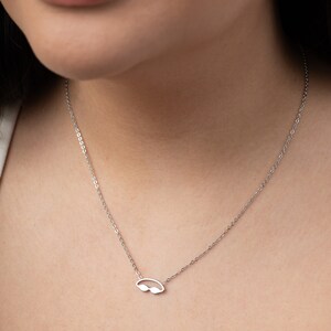 May include: A silver chain necklace with a small, silver, cutout pendant shaped like a pair of swimming goggles.
