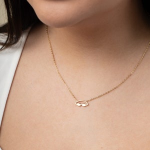 May include: A gold chain necklace with a small, delicate pendant shaped like a pair of sunglasses.