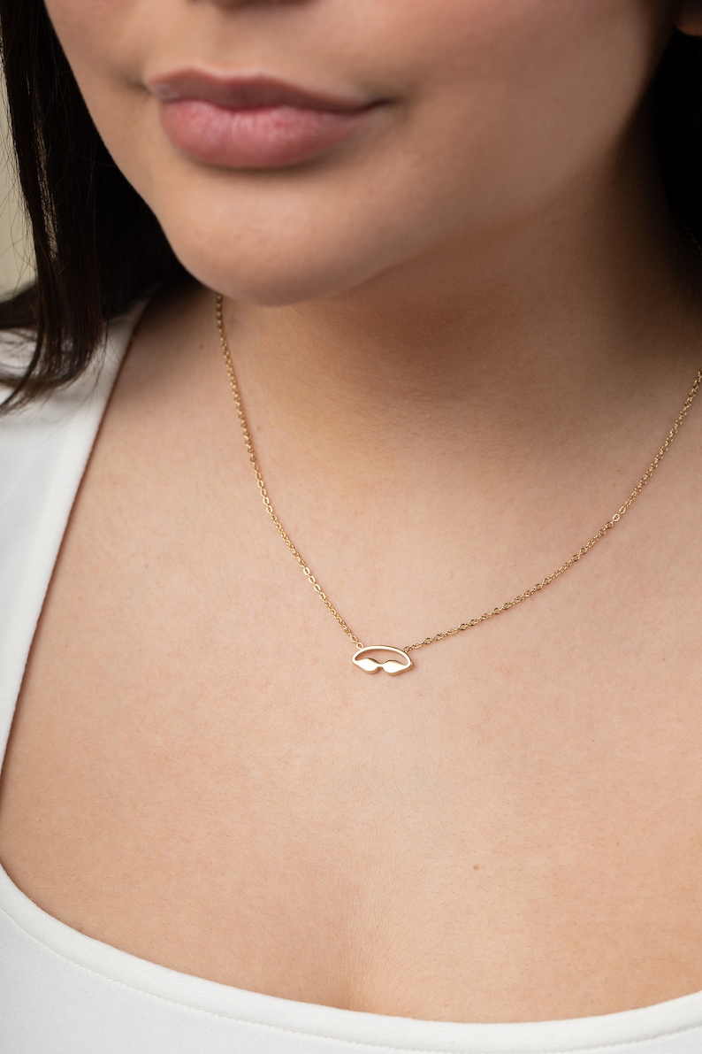 May include: A gold chain necklace with a small, delicate pendant shaped like a pair of sunglasses.