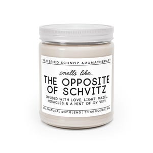 May include: A white candle jar with a silver lid. The label reads "SATISFIED SCHNOZ AROMATHERAPY" and "smells like... THE OPPOSITE OF SCHVITZ". The label also says "INFUSED WITH LOVE, LIGHT, MAZEL, MIRACLES & A HINT OF OY VEY!" and "ALL-NATURAL SOY BLEND | 50-60 HOURS | 9oz".