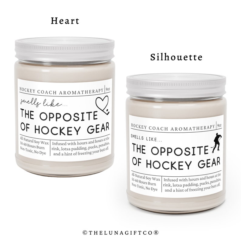 May include: Two soy wax candles with silver lids. The candles are labeled "Hockey Coach Aromatherapy" and have the text "The Opposite of Hockey Gear" on the front. One candle has a heart icon and the other has a hockey player silhouette.