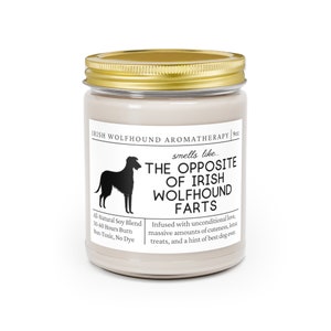 May include: A candle in a glass jar with a gold lid. The label reads "Irish Wolfhound Aromatherapy" and "smells like... THE OPPOSITE OF IRISH WOLFHOUND FARTS." It also states "All-Natural Soy Blend" and "50-60 Hours Burn."