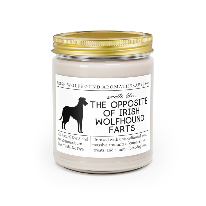 May include: A candle in a glass jar with a gold lid. The label reads "Irish Wolfhound Aromatherapy" and "smells like... THE OPPOSITE OF IRISH WOLFHOUND FARTS." It also states "All-Natural Soy Blend" and "50-60 Hours Burn."