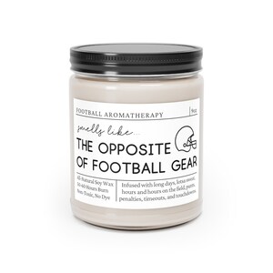 Może przedstawiać: Świeca o pojemności 9 uncji w szklanym słoiku z czarną pokrywką. Etykieta głosi "Football Aromatherapy smells like... THE OPPOSITE OF FOOTBALL GEAR" i zawiera informacje o świecy, takie jak rodzaj wosku, czas palenia i nuty zapachowe. Zapach opisany jest jako "Infused with long days, lotsa sweat, hours and hours on the field, punts, penalties, timeouts, and touchdowns."