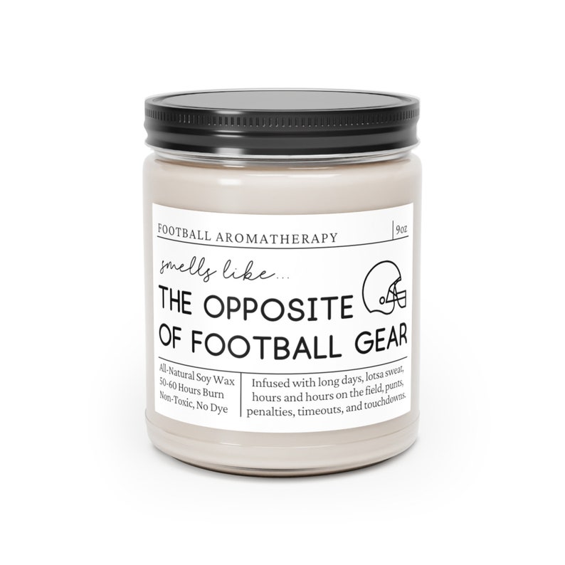 Może przedstawiać: Świeca o pojemności 9 uncji w szklanym słoiku z czarną pokrywką. Etykieta głosi "Football Aromatherapy smells like... THE OPPOSITE OF FOOTBALL GEAR" i zawiera informacje o świecy, takie jak rodzaj wosku, czas palenia i nuty zapachowe. Zapach opisany jest jako "Infused with long days, lotsa sweat, hours and hours on the field, punts, penalties, timeouts, and touchdowns."