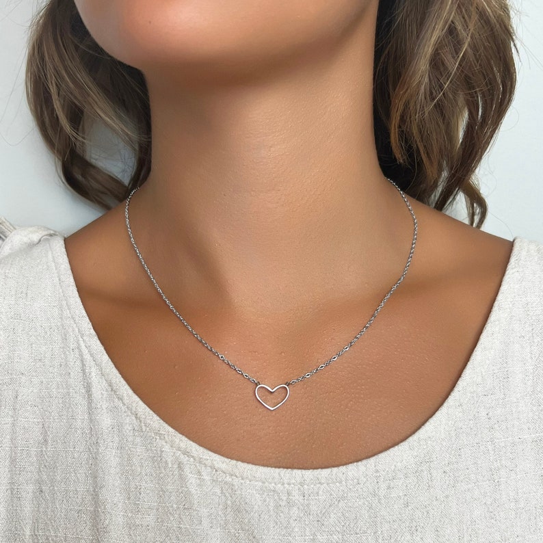 May include: A silver chain necklace with a delicate open heart pendant.