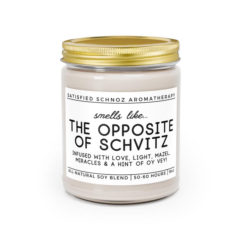 May include: A white candle jar with a gold lid. The label reads "SATISFIED SCHNOZ AROMATHERAPY" and "smells like... THE OPPOSITE OF SCHVITZ". The label also says "INFUSED WITH LOVE, LIGHT, MAZEL, MIRACLES & A HINT OF OY VEY!" and "ALL-NATURAL SOY BLEND | 50-60 HOURS | 9oz".