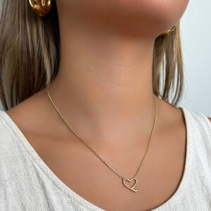Op de afbeelding: Een gouden ketting met een eenvoudige hartvormige hanger.