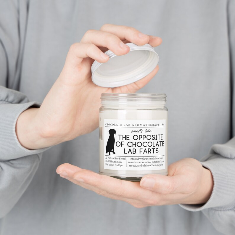 Może przedstawiać: Biały słoik ze świecą z czarną sylwetką psa na etykiecie. Etykieta zawiera napis "Chocolate Lab Aromatherapy" i "smells like THE OPPOSITE OF CHOCOLATE LAB FARTS".
