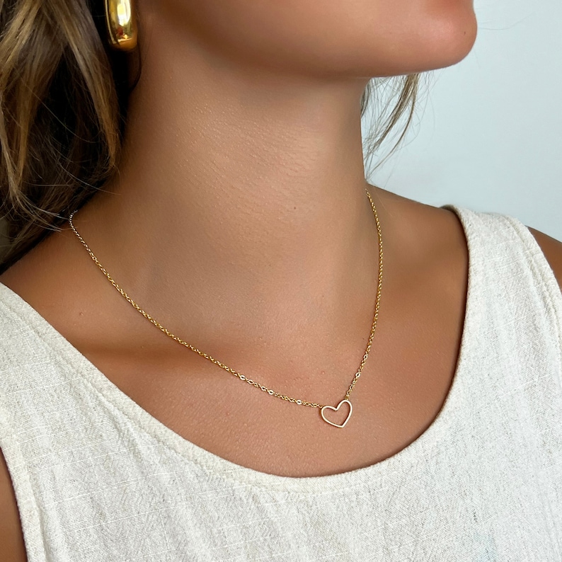 May include: A gold chain necklace with a delicate open heart pendant.