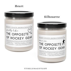 May include: Two glass candle jars with black lids. The jars are filled with a light beige soy wax. The labels on the jars read "Hockey Coach Aromatherapy" and "Smells Like... The Opposite of Hockey Gear". One jar has a heart icon and the other has a hockey player silhouette.