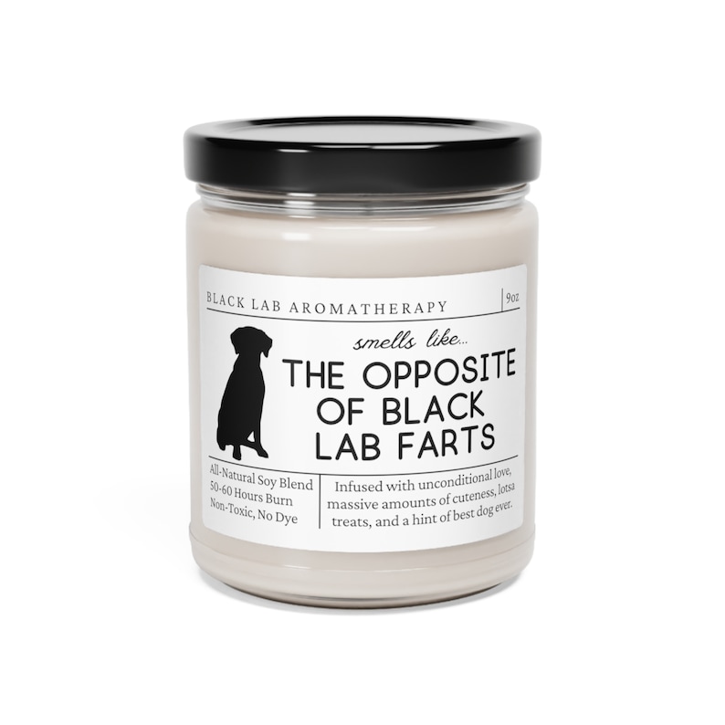 May include: A white candle jar with a black lid and label. The label reads "BLACK LAB AROMATHERAPY" and "smells like... THE OPPOSITE OF BLACK LAB FARTS". The label also includes the text "All-Natural Soy Blend, 50-60 Hours Burn, Non-Toxic, No Dye" and "Infused with unconditional love, massive amounts of cuteness, lotsa treats, and a hint of best dog ever."
