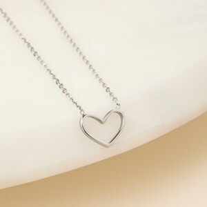 May include: A silver chain necklace with a delicate open heart pendant.