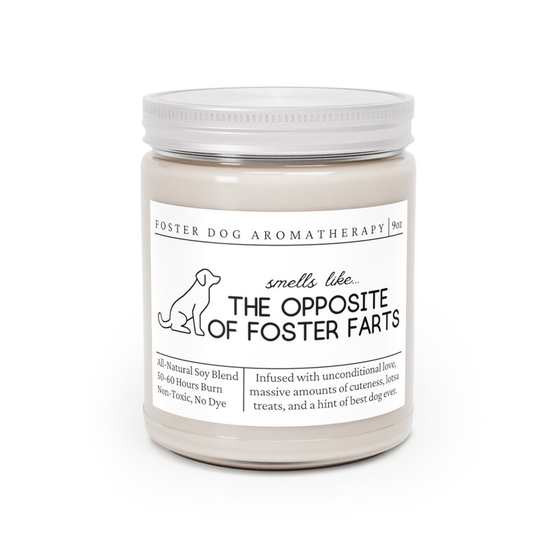 May include: A beige candle jar with a silver lid. The label reads "Foster Dog Aromatherapy" and "smells like... THE OPPOSITE OF FOSTER FARTS". The candle is made with all-natural soy blend and has a 50-60 hour burn time. It is non-toxic and dye-free.