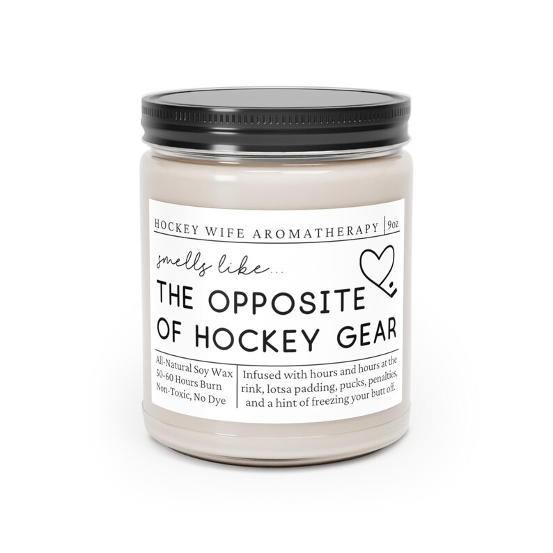 May include: A 9oz candle in a glass jar with a black lid. The label reads "Hockey Wife Aromatherapy" and "smells like... THE OPPOSITE OF HOCKEY GEAR". The candle is infused with scents of a hockey rink, padding, pucks, penalties, and a hint of freezing your butt off. The candle is made with all-natural soy wax and has a burn time of 50-60 hours.