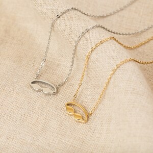 May include: Two gold and silver necklaces with a small, open-circle pendant shaped like a pair of sunglasses.