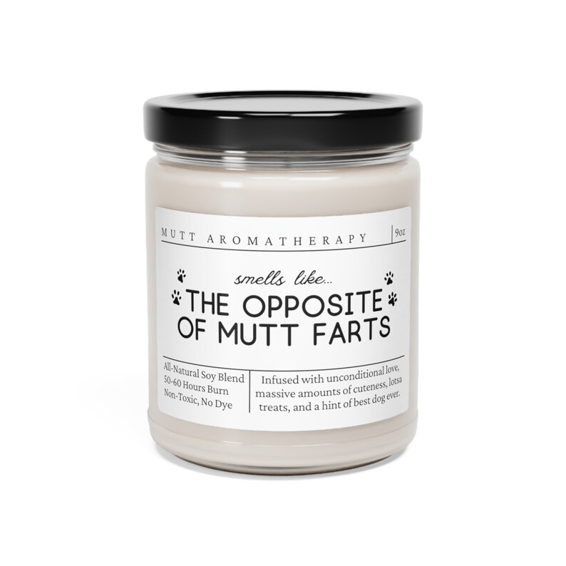 May include: A white candle jar with a black lid. The label reads "Mutt Aromatherapy" and "smells like... THE OPPOSITE OF MUTT FARTS". The candle is made with all-natural soy blend, burns for 50-60 hours, and is non-toxic and dye-free. The candle is infused with unconditional love, massive amounts of cuteness, lotsa treats, and a hint of best dog ever.