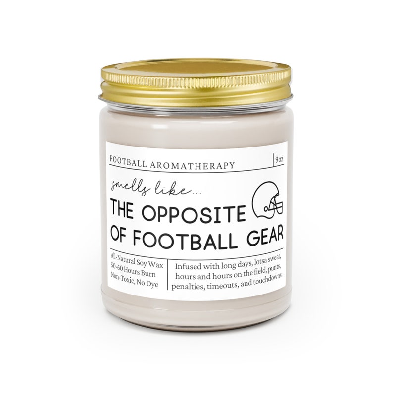 Może przedstawiać: Świeca o pojemności 9 uncji w szklanym słoiku z pokrywką w kolorze złotym. Etykieta zawiera napis "Football Aromatherapy smells like... The Opposite of Football Gear". Etykieta zawiera r&oacute;wnież informacje o świecy, takie jak rodzaj wosku, czas palenia i składniki.