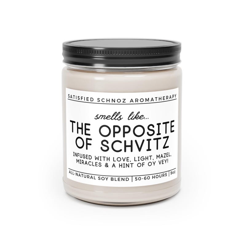 May include: A glass jar candle with a black lid and a white label that reads "SATISFIED SCHNOZ AROMATHERAPY smells like... THE OPPOSITE OF SCHVITZ INFUSED WITH LOVE, LIGHT, MAZEL, MIRACLES & A HINT OF OY VEY! ALL-NATURAL SOY BLEND 50-60 HOURS 9oz"