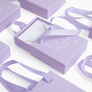 Op de afbeelding: Een set van lavendelkleurige cadeaudoosjes met een wit lint en een wit logo met de tekst "Luna Gift Co." met een halve maan en sterren. De doosjes zijn perfect om kleine cadeautjes in te verpaken.