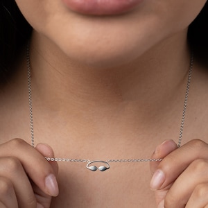 May include: A silver chain necklace with a small silver pendant shaped like a pair of swimming goggles.