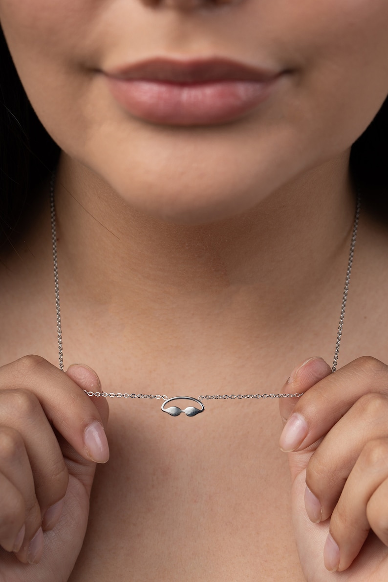 May include: A silver chain necklace with a small silver pendant shaped like a pair of swimming goggles.