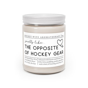 May include: A 9oz soy wax candle in a glass jar with a silver lid. The candle is labeled "Hockey Wife Aromatherapy" and says "smells like... The Opposite of Hockey Gear". The candle is infused with scents of a hockey rink, padding, pucks, penalties, and a hint of freezing your butt off. The candle is all-natural, non-toxic, and dye-free.
