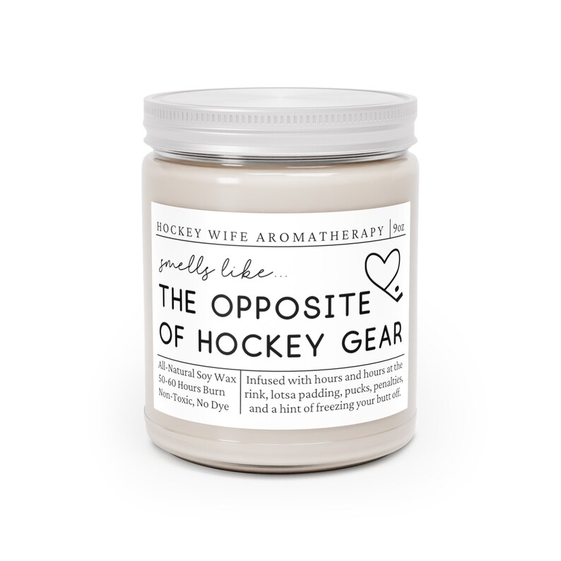 May include: A 9oz soy wax candle in a glass jar with a silver lid. The candle is labeled "Hockey Wife Aromatherapy" and says "smells like... The Opposite of Hockey Gear". The candle is infused with scents of a hockey rink, padding, pucks, penalties, and a hint of freezing your butt off. The candle is all-natural, non-toxic, and dye-free.