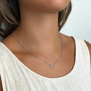 May include: A silver chain necklace with a delicate open heart pendant.