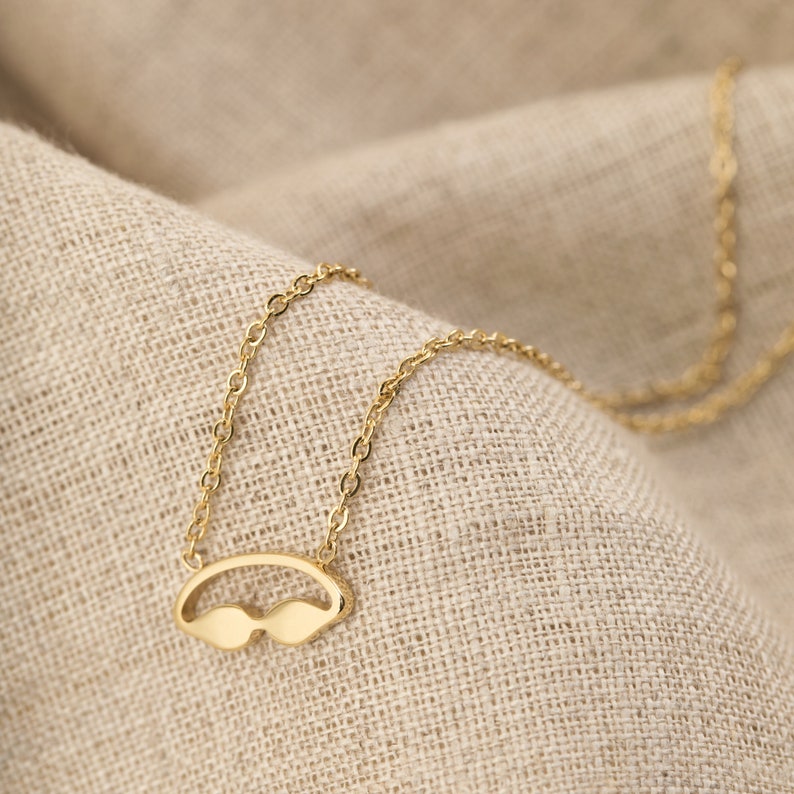 May include: A gold chain necklace with a pendant shaped like a pair of sunglasses.