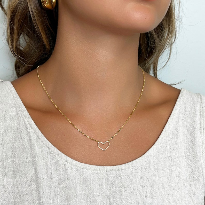 May include: A gold chain necklace with a delicate open heart pendant.