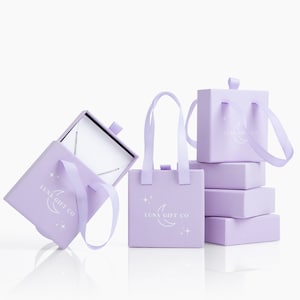May include: Four lavender gift boxes with white handles and the text "Luna Gift Co." and a crescent moon design. One box is open and shows a silver necklace inside.