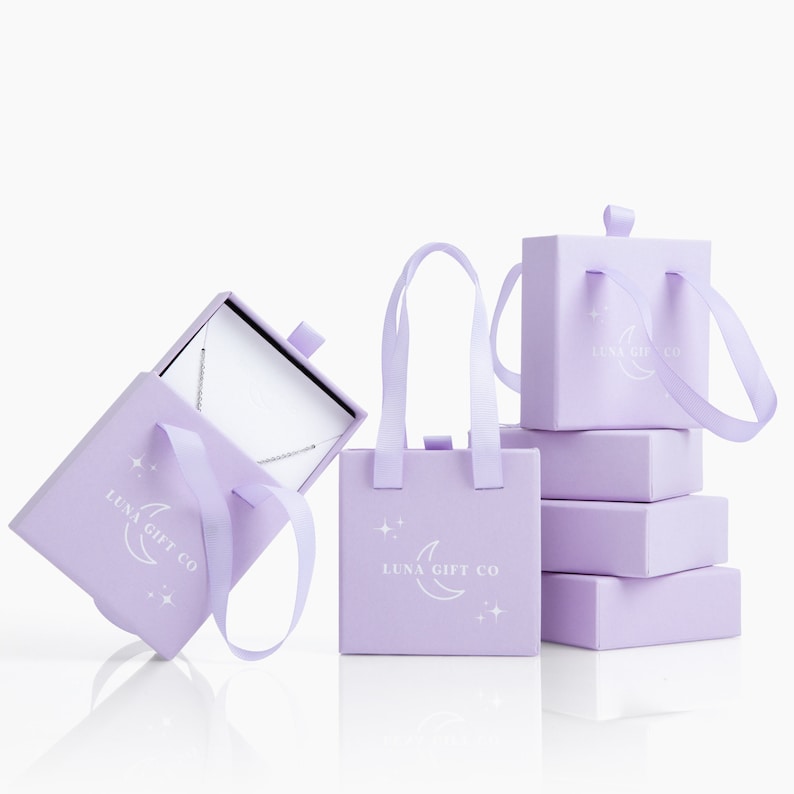 May include: Four lavender gift boxes with white handles and the text "Luna Gift Co." and a crescent moon design. One box is open and shows a silver necklace inside.