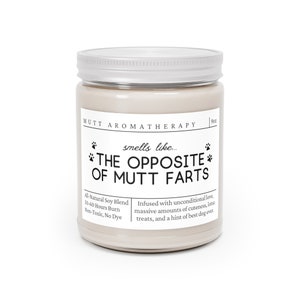 May include: A white candle jar with a silver lid. The label reads "Mutt Aromatherapy" and "smells like... THE OPPOSITE OF MUTT FARTS". The candle is made with a natural soy blend and has a burn time of 50-60 hours.