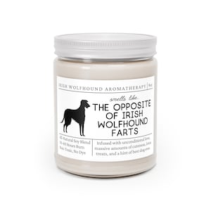 May include: A cream-coloured aromatherapy candle in a glass jar with a white lid. The label features a black silhouette of an Irish Wolfhound and the text "THE OPPOSITE OF IRISH WOLFHOUND FARTS". The candle is an all-natural soy blend.