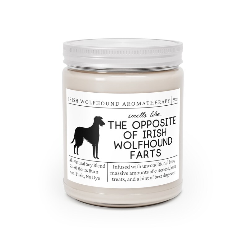 May include: A cream-coloured aromatherapy candle in a glass jar with a white lid. The label features a black silhouette of an Irish Wolfhound and the text "THE OPPOSITE OF IRISH WOLFHOUND FARTS". The candle is an all-natural soy blend.