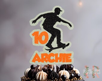 May include: Orange and white cake topper with a silhouette of a person skateboarding. The topper says "10 ARCHIE" in orange letters.