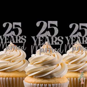 May include: Three cupcakes with white frosting and silver glitter cake toppers that read "25 Years Married" against a black background. The cupcakes are in white paper liners.