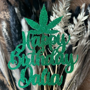 May include: Green glitter cake topper featuring a marijuana leaf design and the text "Happy Birthday Dalila".