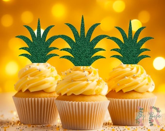 Puede incluir: Tres cupcakes amarillos con adornos de piña de purpurina verde. Los cupcakes están decorados con chispas plateadas.