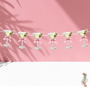May include: A pink and green party banner with a string of martini glasses with olives. The glasses have pink bows on the stems.