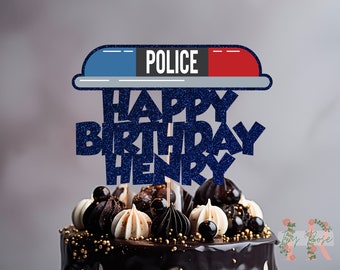 Könnte beinhalten: Blau-roter Polizeiwagen-Licht-Kuchentopper mit dem Wort "POLICE" darauf. Der Topper befindet sich auf einem Schokoladenkuchen mit weiß-schwarzem Frosting und goldenen Streuseln. Der Kuchentopper sagt auch "Happy Birthday Henry" in blauen Glitzerbuchstaben.