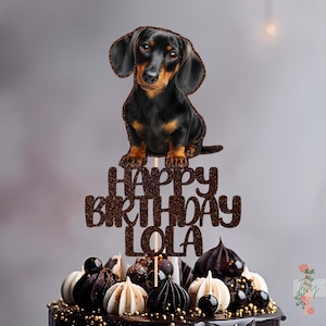 Peut inclure: Décoration de gâteau avec un teckel et l'inscription "HAPPY BIRTHDAY LOLA" en paillettes marron. Le chien est noir et marron, perché au-dessus d'un gâteau décoré avec des accents chocolat et blancs. Une décoration festive pour un anniversaire.