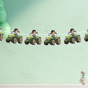 May include: A banner featuring green tractors, each with a child's face, strung on a white string. The tractors have yellow wheels. Green balloons are in the upper left. The background is a light green wall.