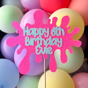 Può includere: Topper per torta di glitter rosa con un design a spruzzo di vernice rosa. Il topper dice "Happy 6th Birthday Eve" in lettere di glitter argentate.