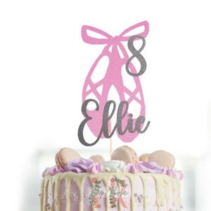 Könnte beinhalten: Rosa glitzernder Ballerinaschuh-Kuchentopper mit einer silbernen Glitzer Schleife und der Zahl 8. Der Name Ellie ist in silbernem Glitter unter dem Schuh geschrieben.