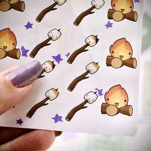 Close up of sticker sheet with cute marshmallows toasted the campfire, cute sweethearts cuddling by the fire.