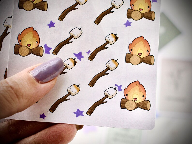 Close up of sticker sheet with cute marshmallows toasted the campfire, cute sweethearts cuddling by the fire.