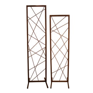 Op de afbeelding: Twee vrijstaande roomdividers van bruin metaal met een kruispatroon. De dividers zijn hoog en smal.