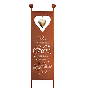 Op de afbeelding: Een roestig metalen tuinschild met een hartvormige uitsparing en een hangend hart ornament. Het bord staat "Wo sich dein Herz wohlfühlt, ist dein Zuhause" wat vertaalt wordt naar "Waar je hart zich goed voelt, is je thuis".